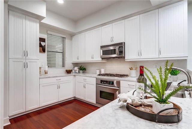 395 E 4th St Unit 13, Long Beach, CA 90802 - kitchen with appliances with stainless steel finishes, dark wood finished floors, white cabinets, tasteful backsplash, and recessed lighting