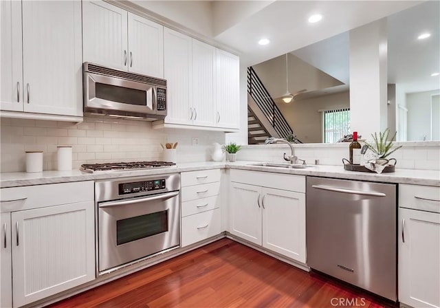 395 E 4th St Unit 13, Long Beach, CA 90802 - kitchen with stainless steel appliances, a sink, dark wood-type flooring, decorative backsplash, and white cabinets