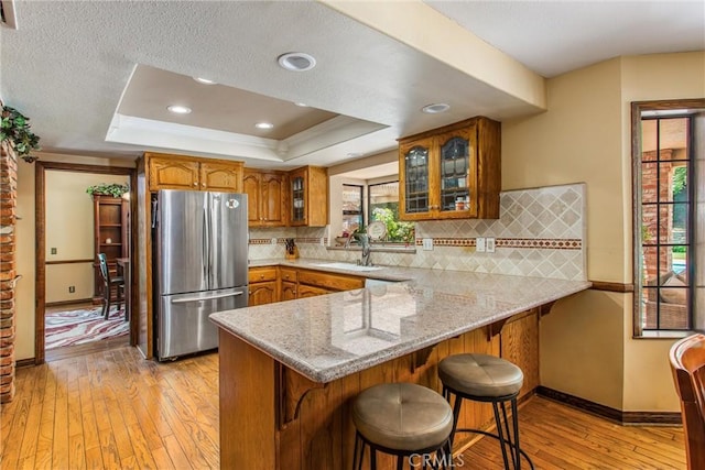 639 Valley View Dr, Redlands, CA 92373 - kitchen with freestanding refrigerator, brown cabinetry, a peninsula, a sink, and light wood-style flooring