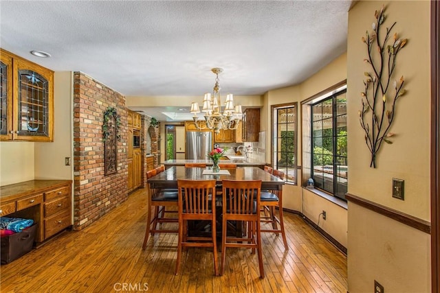 639 Valley View Dr, Redlands, CA 92373 - dining space with hardwood / wood-style flooring, a chandelier, a textured ceiling, brick wall, and baseboards