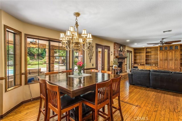 639 Valley View Dr, Redlands, CA 92373 - dining area with light wood finished floors, a fireplace, a chandelier, baseboards, and a ceiling fan