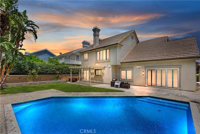 7000 Fabriano Pl, Rancho Cucamonga, CA 91701 - back of property at dusk with stucco siding, a balcony, a patio, a tiled roof, and a chimney
