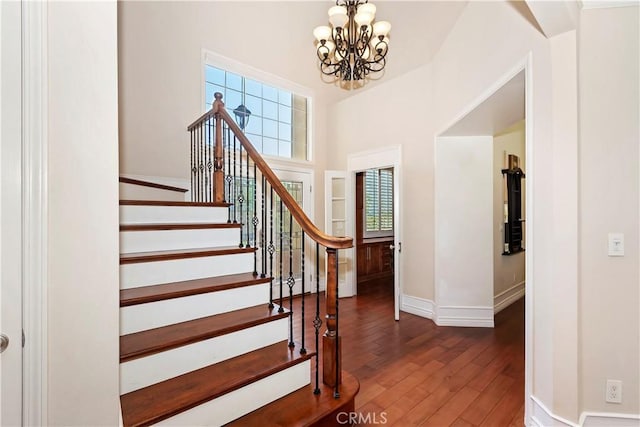 7000 Fabriano Pl, Rancho Cucamonga, CA 91701 - staircase featuring a chandelier, hardwood / wood-style floors, baseboards, and a towering ceiling