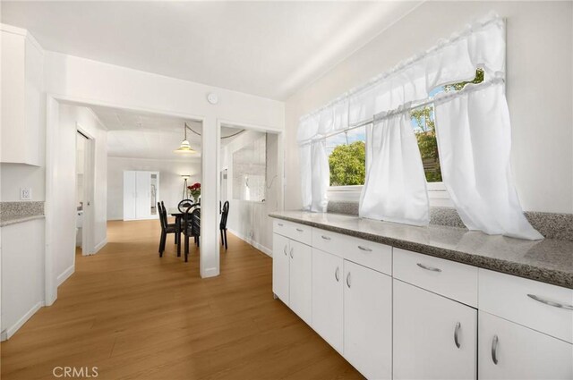 11705 Adonis Ave, Norwalk, CA 90650 - kitchen featuring light wood-type flooring, white cabinets, and dark stone countertops