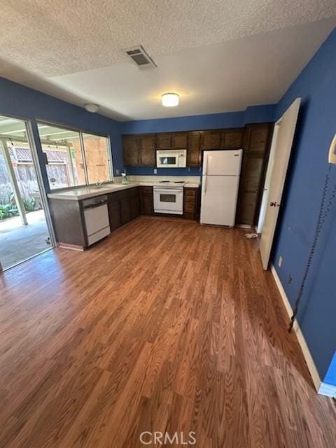 869 El Portal Dr, Merced, CA 95340 - kitchen featuring white appliances, wood finished floors, a textured ceiling, baseboards, and light countertops