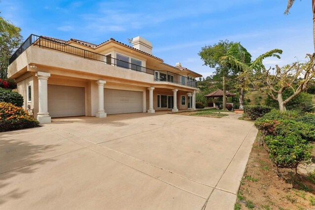 1320 Sleeping Indian Rd, Oceanside, CA 92057 - mediterranean / spanish-style home featuring a balcony, a chimney, a gazebo, stucco siding, and driveway