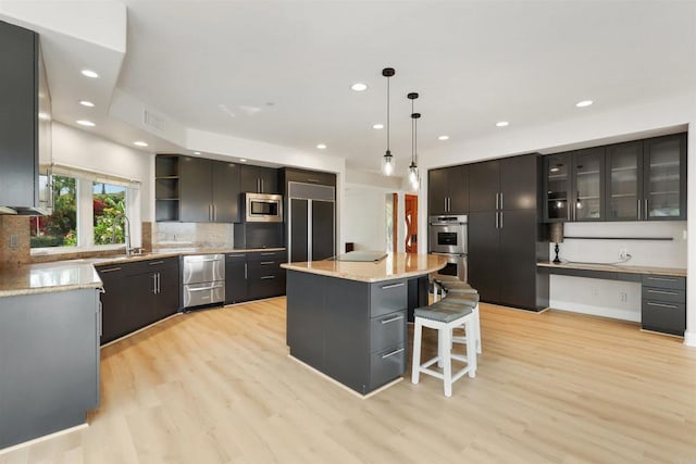 1320 Sleeping Indian Rd, Oceanside, CA 92057 - kitchen featuring built in appliances, open shelves, light wood-style floors, a kitchen island, and backsplash