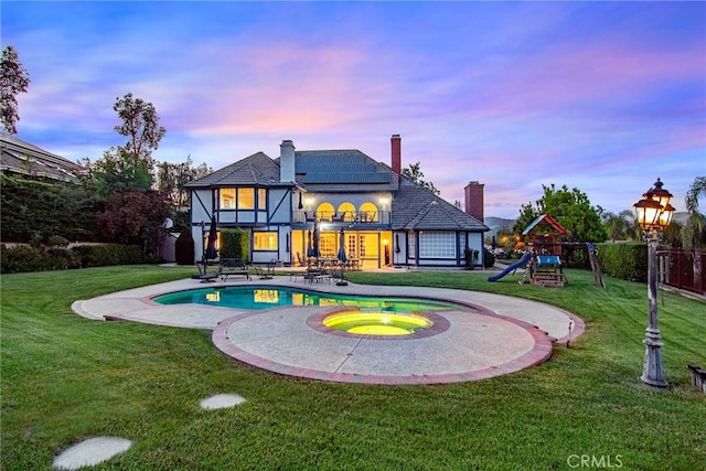 29302 Laro Dr, Agoura Hills, CA 91301 - back of house featuring solar panels, a patio, a chimney, a playground, and a pool with connected hot tub