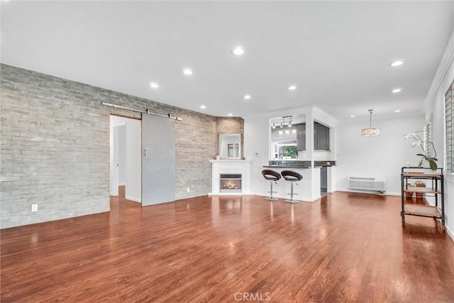 601 Olive Ave Unit L, Long Beach, CA 90802 - living area featuring recessed lighting, a barn door, wood finished floors, a glass covered fireplace, and baseboards