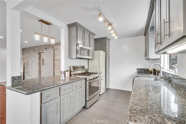 601 Olive Ave Unit L, Long Beach, CA 90802 - kitchen with appliances with stainless steel finishes, a sink, gray cabinetry, dark stone counters, and pendant lighting