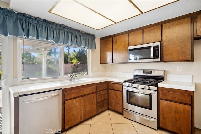 663 Redwood Ave, Upland, CA 91786 - kitchen featuring appliances with stainless steel finishes, a sink, brown cabinets, and tile countertops