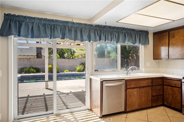 663 Redwood Ave, Upland, CA 91786 - kitchen with stainless steel dishwasher, tile counters, a sink, light tile patterned floors, and brown cabinetry