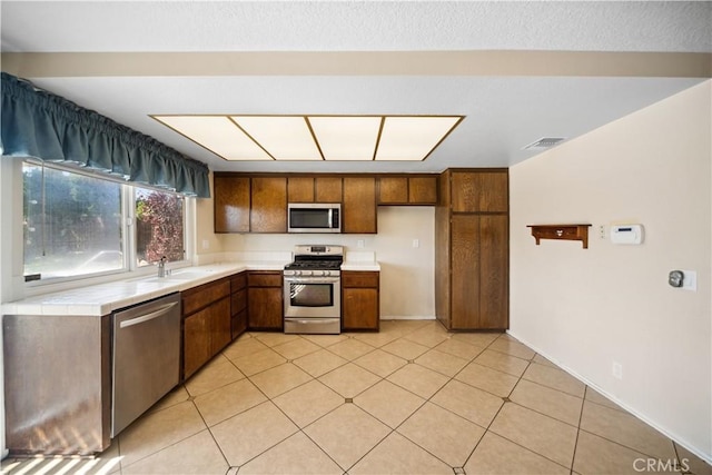 663 Redwood Ave, Upland, CA 91786 - kitchen featuring appliances with stainless steel finishes, a sink, brown cabinetry, and light tile patterned floors