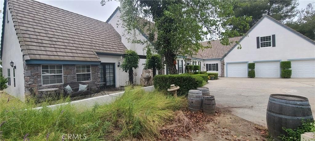 43275 Calle Capistrano, Temecula, CA 92590 - view of side of home featuring stucco siding, concrete driveway, and stone siding
