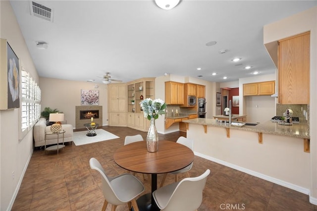 5675 W Overlook Dr, Rancho Cucamonga, CA 91739 - dining area featuring a warm lit fireplace, a ceiling fan, baseboards, and recessed lighting