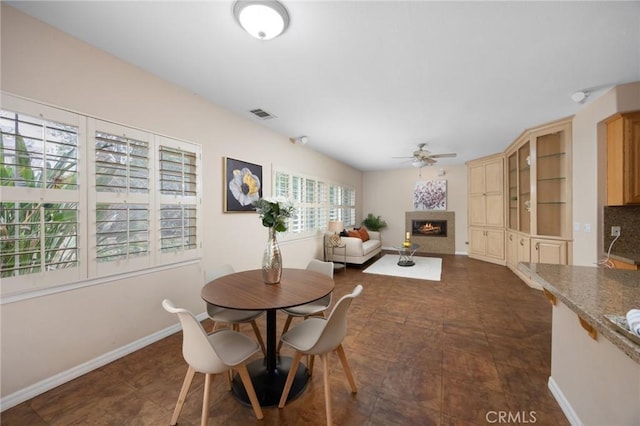 5675 W Overlook Dr, Rancho Cucamonga, CA 91739 - dining space featuring a ceiling fan, a lit fireplace, and baseboards
