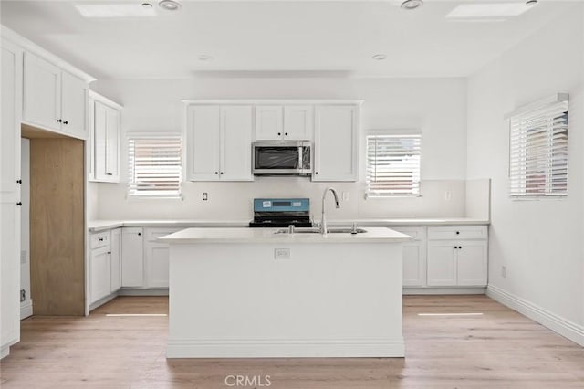941 E 97th St, Los Angeles, CA 90002 - kitchen with stainless steel microwave, range, a sink, an island with sink, and white cabinetry