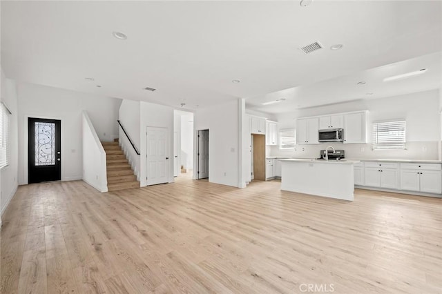 941 E 97th St, Los Angeles, CA 90002 - unfurnished living room with light wood-style flooring, stairs, recessed lighting, and baseboards