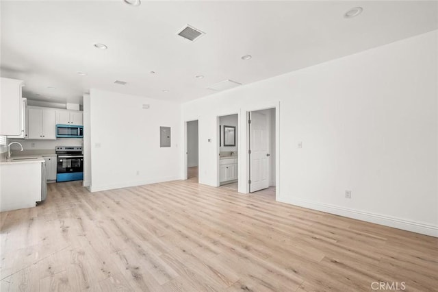 941 E 97th St, Los Angeles, CA 90002 - unfurnished living room featuring electric panel, light wood finished floors, a sink, baseboards, and recessed lighting