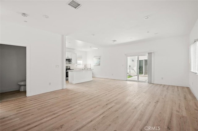 941 E 97th St, Los Angeles, CA 90002 - unfurnished living room with light wood-style floors, baseboards, and a sink