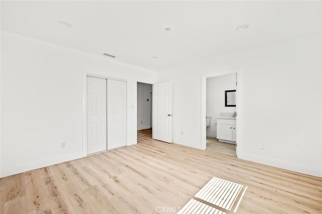 941 E 97th St, Los Angeles, CA 90002 - unfurnished bedroom with light wood-style flooring, a closet, baseboards, and connected bathroom