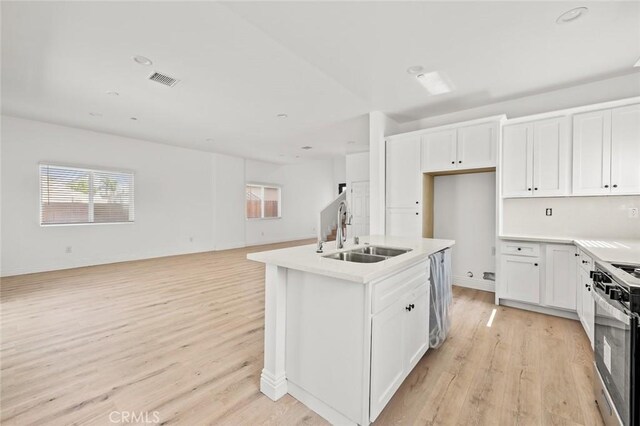 941 E 97th St, Los Angeles, CA 90002 - kitchen with a sink, stainless steel appliances, light wood finished floors, open floor plan, and white cabinets