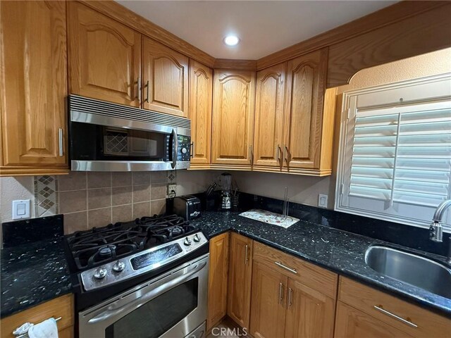 431 W M St, Colton, CA 92324 - kitchen with stainless steel appliances, a sink, dark stone counters, backsplash, and brown cabinets