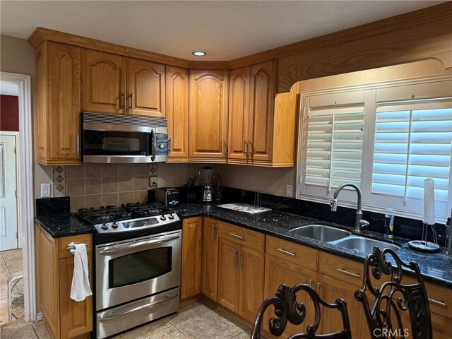 431 W M St, Colton, CA 92324 - kitchen featuring stainless steel appliances, a sink, brown cabinetry, dark stone countertops, and decorative backsplash