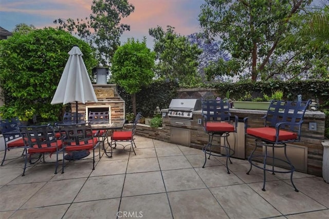 8 Marston Ln, Ladera Ranch, CA 92694 - patio terrace at dusk with a patio area, outdoor dining space, and a glass covered fireplace