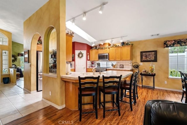 2860 Cathedral Ln, Arroyo Grande, CA 93420 - kitchen featuring rail lighting, appliances with stainless steel finishes, a kitchen bar, a peninsula, and tile counters