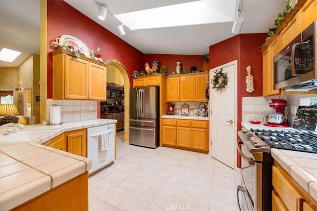 2860 Cathedral Ln, Arroyo Grande, CA 93420 - kitchen featuring appliances with stainless steel finishes, tile counters, rail lighting, decorative backsplash, and a skylight
