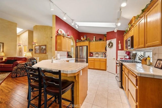 2860 Cathedral Ln, Arroyo Grande, CA 93420 - kitchen with stainless steel appliances, track lighting, a sink, a peninsula, and tile countertops