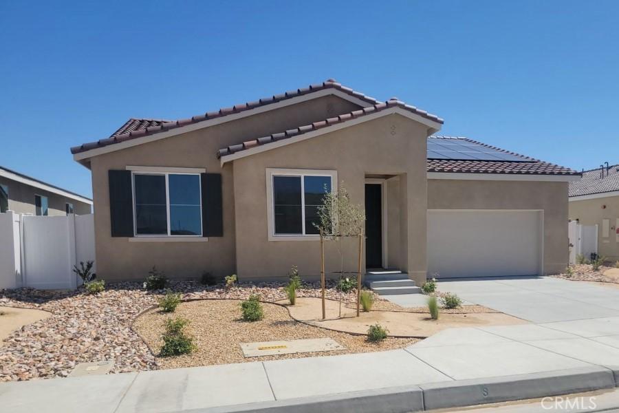1600 E E Ave H7, Lancaster, CA 93535 - view of front of home with a garage, stucco siding, roof mounted solar panels, and driveway