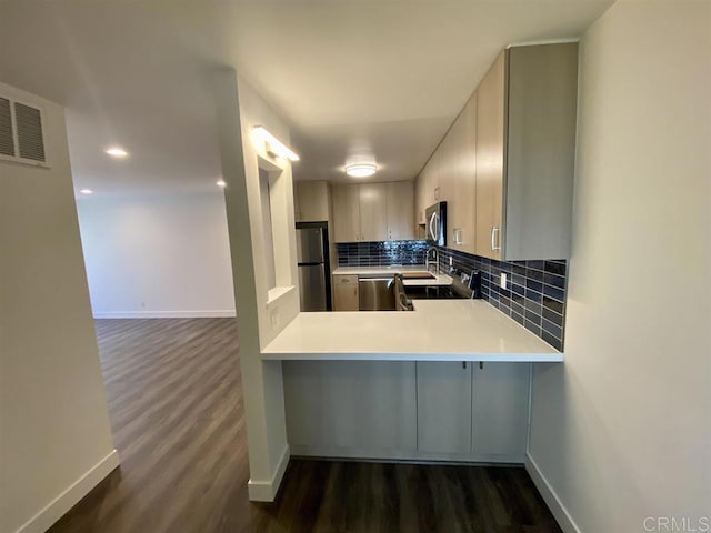 745 E Bradley Ave Unit 27, El Cajon, CA 92021 - kitchen with appliances with stainless steel finishes, dark wood finished floors, decorative backsplash, light countertops, and a peninsula