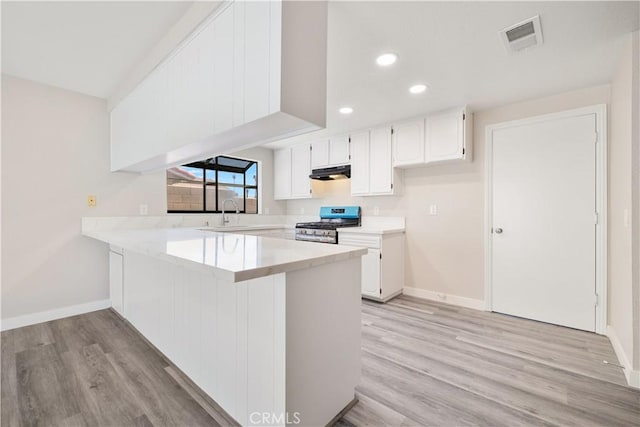 27505 Ventura Dr, Cathedral City, CA 92234 - kitchen with stainless steel gas range oven, under cabinet range hood, a peninsula, baseboards, and recessed lighting