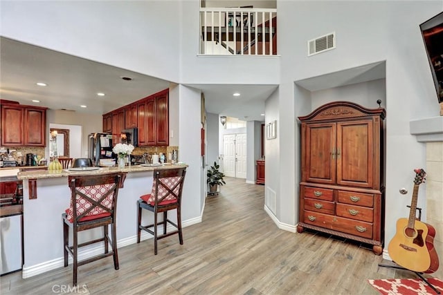 3506 Belvedere Way, Corona, CA 92882 - kitchen featuring light wood-style floors, a breakfast bar area, backsplash, a peninsula, and a high ceiling