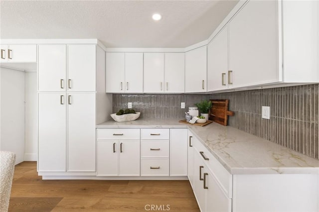 13621 Fairmont Way, Tustin, CA 92780 - kitchen with white cabinetry, light stone countertops, tasteful backsplash, light wood finished floors, and recessed lighting