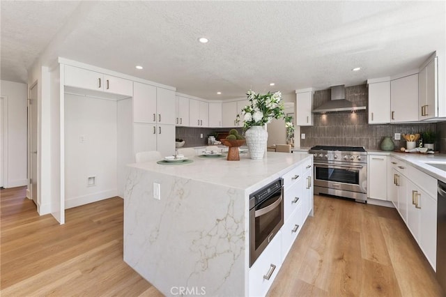 13621 Fairmont Way, Tustin, CA 92780 - kitchen featuring high end stainless steel range oven, wall chimney exhaust hood, tasteful backsplash, a center island, and recessed lighting
