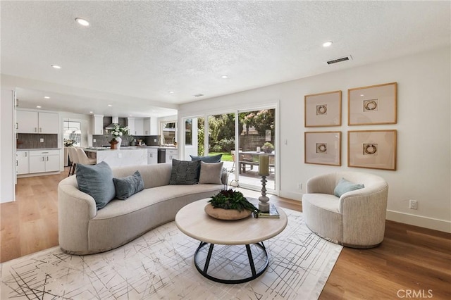 13621 Fairmont Way, Tustin, CA 92780 - living room featuring a textured ceiling, light wood-style flooring, recessed lighting, healthy amount of natural light, and baseboards