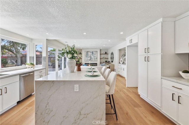13621 Fairmont Way, Tustin, CA 92780 - kitchen featuring stainless steel dishwasher, a textured ceiling, a kitchen breakfast bar, a kitchen island, and white cabinetry