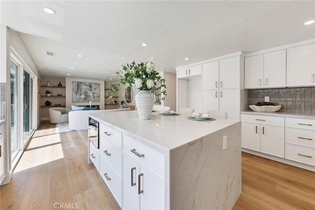 13621 Fairmont Way, Tustin, CA 92780 - kitchen with light wood-style floors, a center island, tasteful backsplash, recessed lighting, and light stone countertops