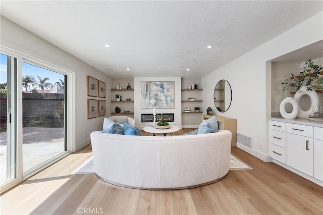 13621 Fairmont Way, Tustin, CA 92780 - living room featuring light wood-type flooring, built in shelves, recessed lighting, a textured ceiling, and baseboards