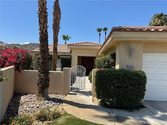 47845 Via Opera Ln, Quinta, CA 92253 - view of front of house with a tile roof, stucco siding, a gate, and an attached garage