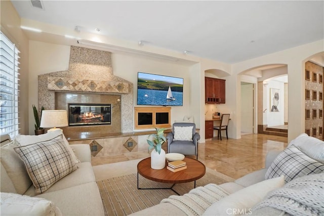 12165 Ojeda Ct, Tustin, CA 92782 - living area featuring arched walkways, light marble finish flooring, and a tiled fireplace