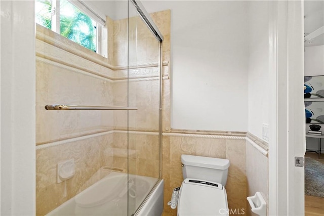 12165 Ojeda Ct, Tustin, CA 92782 - full bathroom featuring toilet, bath / shower combo with glass door, tile walls, and a wainscoted wall