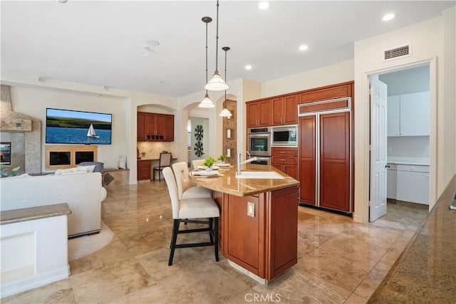 12165 Ojeda Ct, Tustin, CA 92782 - kitchen with built in appliances, a sink, hanging light fixtures, a kitchen bar, and an island with sink