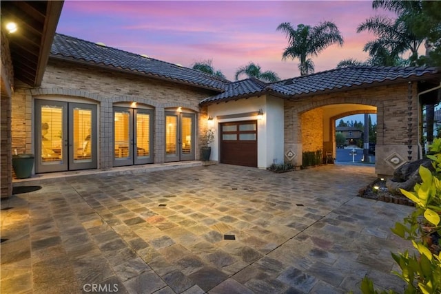 12165 Ojeda Ct, Tustin, CA 92782 - patio terrace at dusk featuring french doors, a garage, and decorative driveway