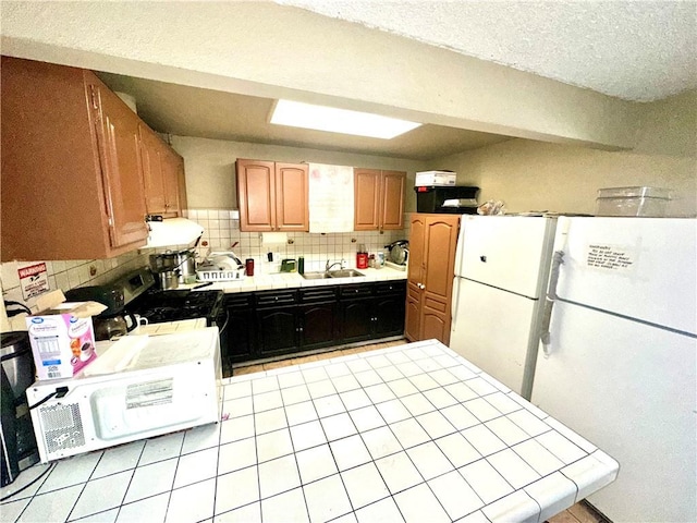 17406 Renault St, La Puente, CA 91744 - kitchen with tile counters, a sink, tasteful backsplash, freestanding refrigerator, and a textured ceiling