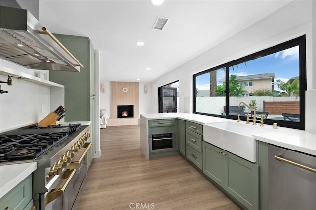 3550 Goldenrod Cir, Seal Beach, CA 90740 - kitchen with green cabinets, wall chimney exhaust hood, a sink, stainless steel appliances, and recessed lighting
