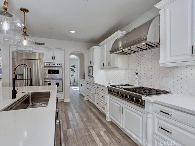 1 Lennox Ct, Ladera Ranch, CA 92694 - kitchen with wall chimney exhaust hood, stainless steel appliances, arched walkways, white cabinets, and recessed lighting